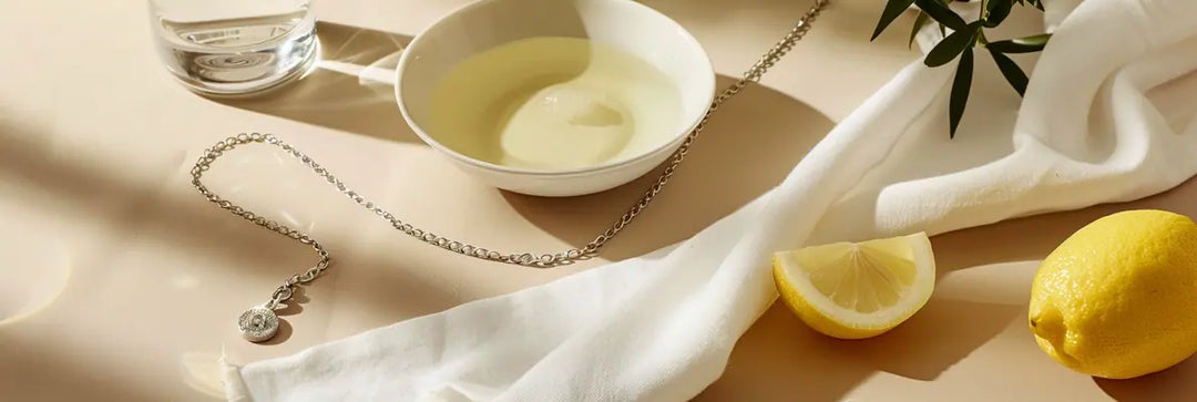 Tarnished silver necklace on white cloth with lemon juice and polishing cloth, cleaning tips for silver jewellery.